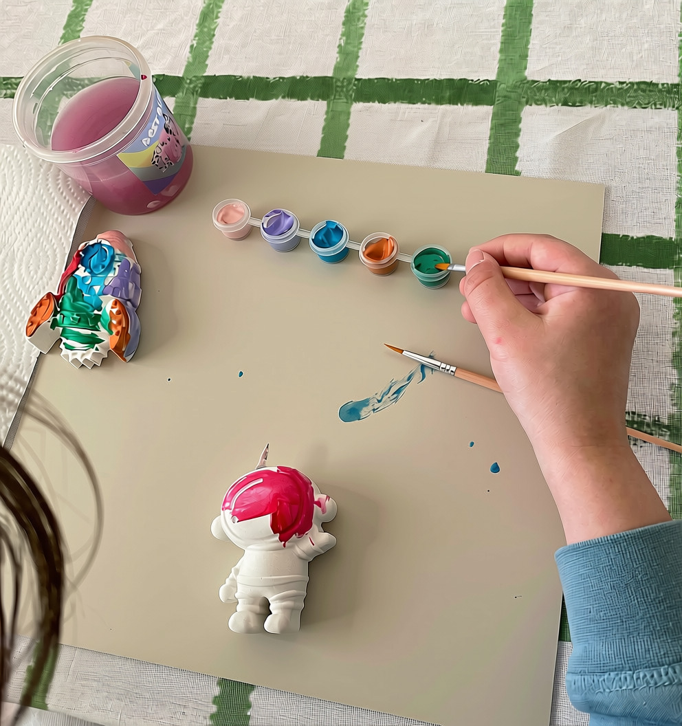 Painted plaster rocket beside an astronaut plaster being painted pink